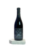 Wine bottle with a label on a white surface against a light gray background