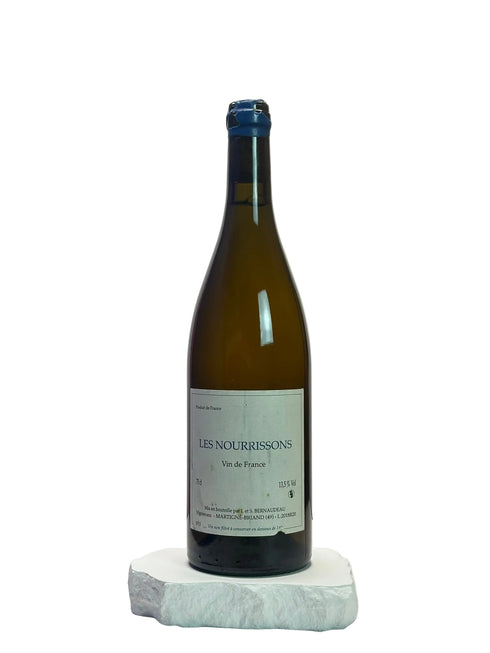 Wine bottle labeled 'Les Nourrissons' on a white surface with a neutral background