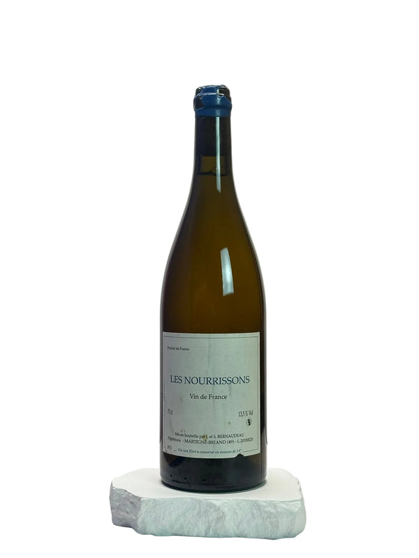 Wine bottle labeled 'Les Nourrissons' on a white surface with a neutral background